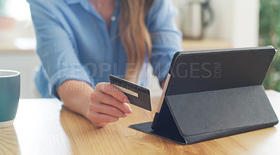 Buy stock photo Cropped shot of a woman holding her credit card while browsing on her digital tablet