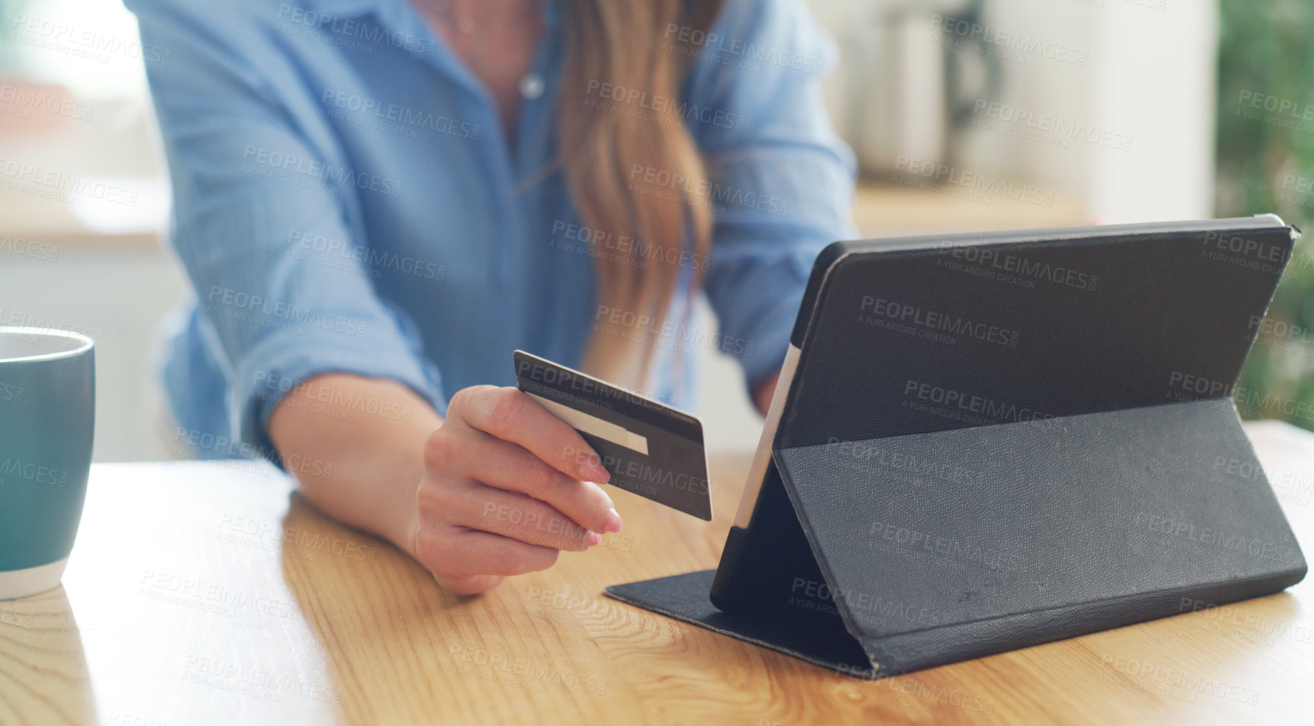 Buy stock photo Cropped shot of a woman holding her credit card while browsing on her digital tablet