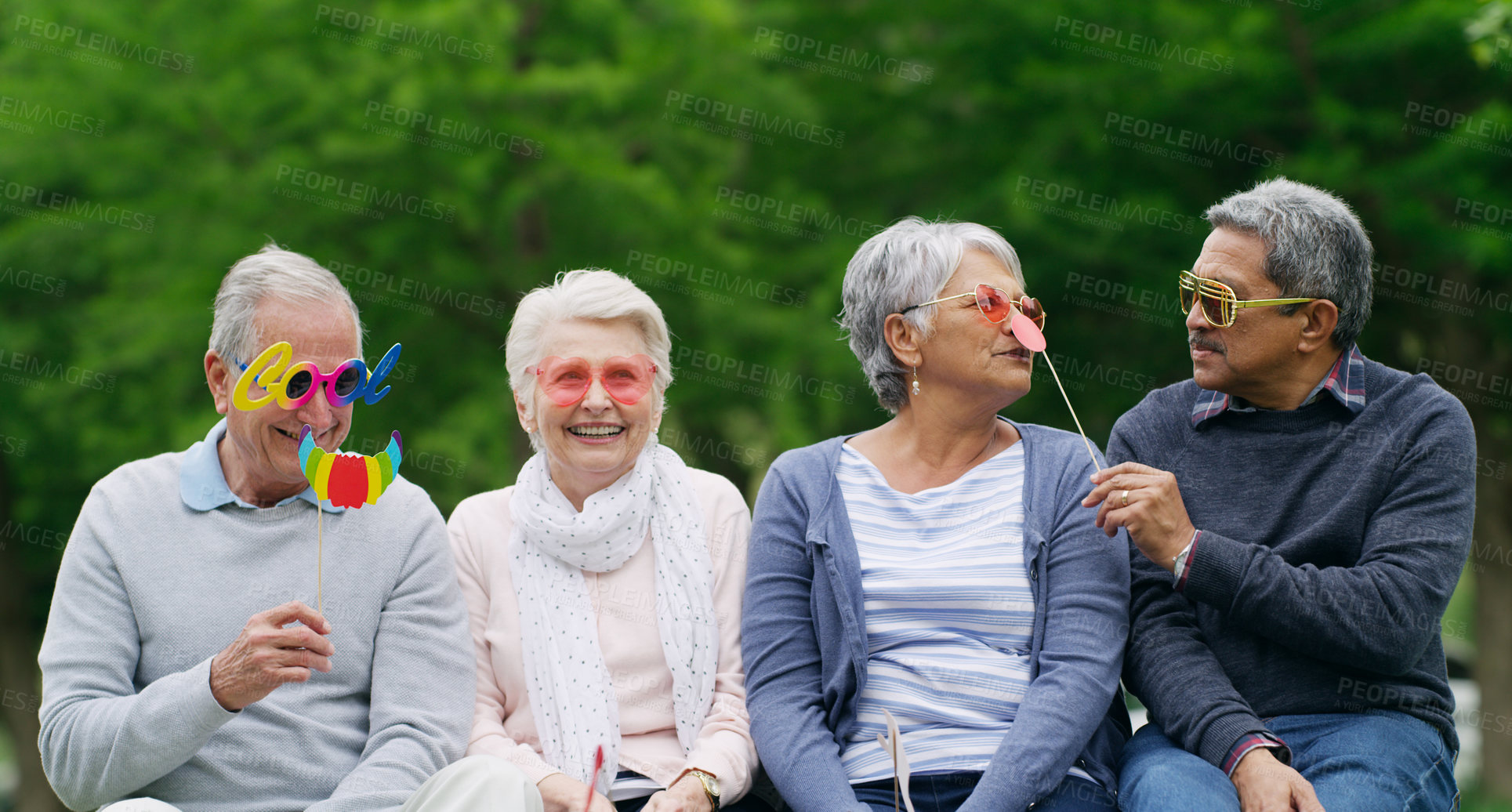 Buy stock photo Shot of a group of happy senior men and women wearing fun glasses at the park