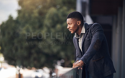 Buy stock photo Shot of a young businessman looking thoughtful while standing on the balcony of an office