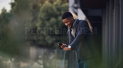 Buy stock photo Shot of a young businessman using a cellphone while standing on the balcony of an office