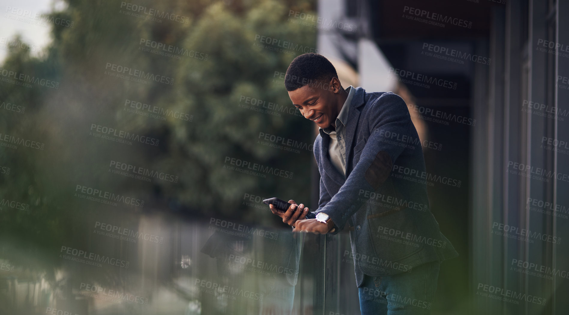 Buy stock photo Shot of a young businessman using a cellphone while standing on the balcony of an office
