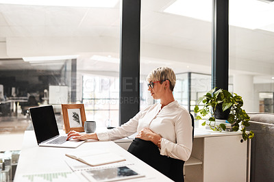 Buy stock photo Shot of a pregnant businesswoman working on a laptop in an office