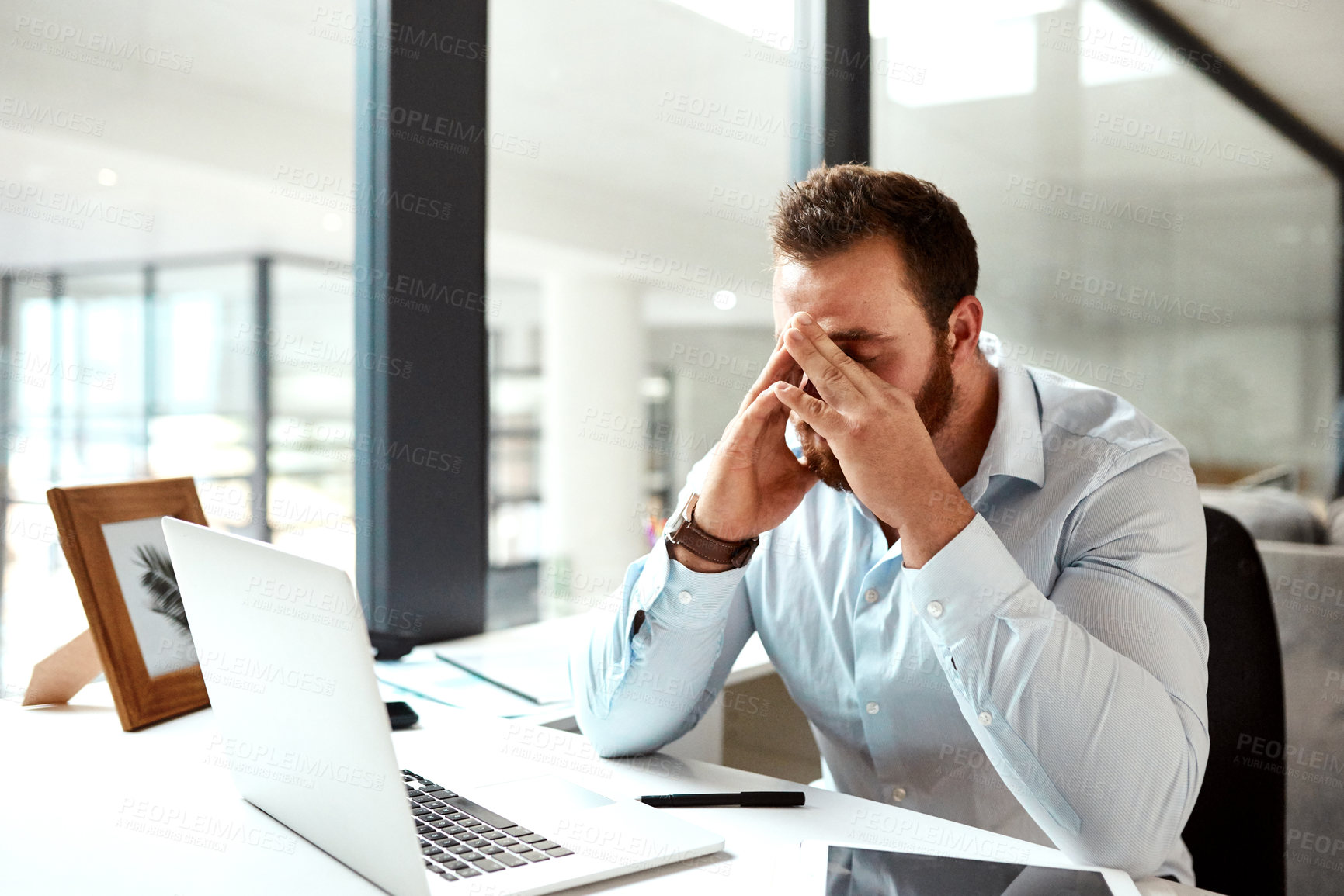 Buy stock photo Shot of a young businessman looking stressed out while working in an office