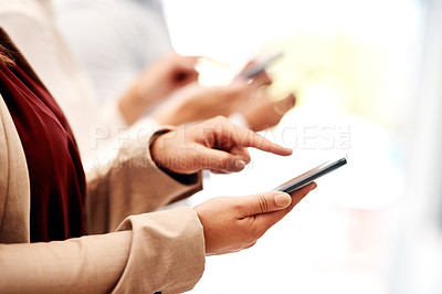 Buy stock photo Closeup shot of an unrecognisable businesswoman using a cellphone with her colleague in the background