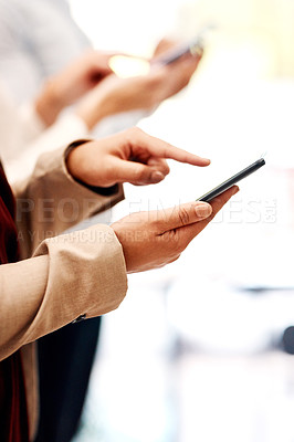 Buy stock photo Closeup shot of an unrecognisable businesswoman using a cellphone with her colleague in the background