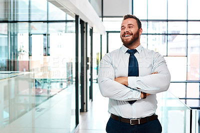 Buy stock photo Shot of a young businessman standing with his arms crossed in an office