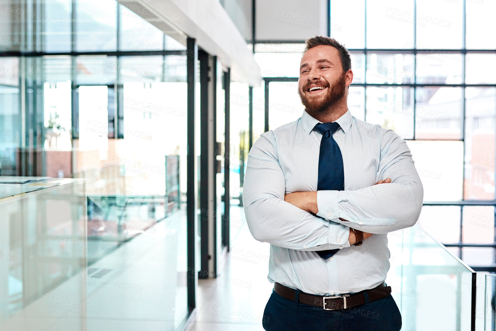 Buy stock photo Shot of a young businessman standing with his arms crossed in an office