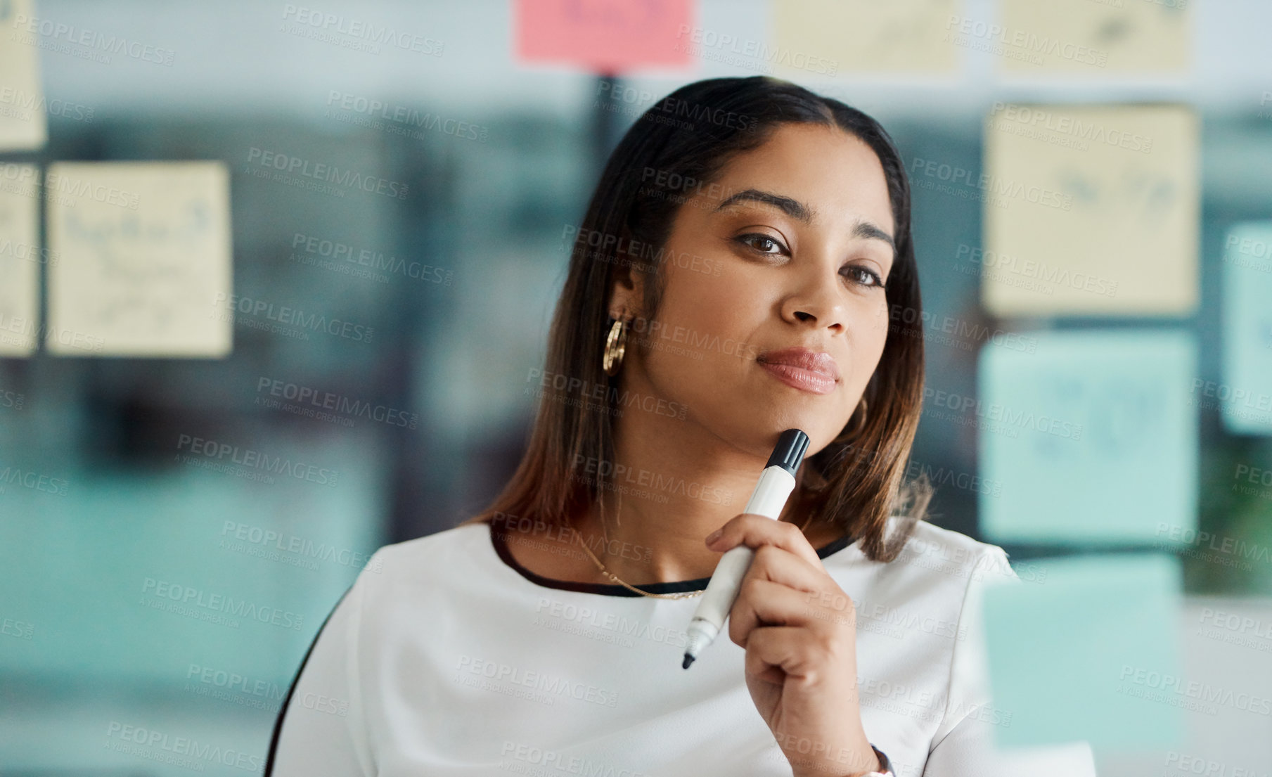 Buy stock photo Shot of a young businesswoman brainstorming with notes on a glass wall in an office