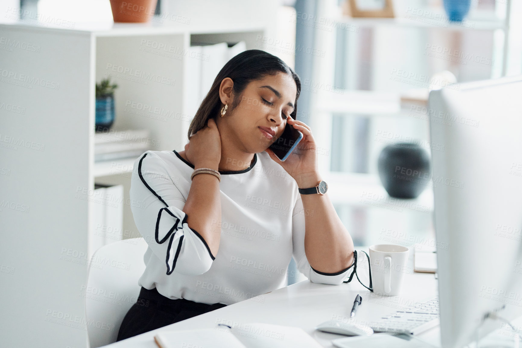Buy stock photo Shot of a young businesswoman rubbing her neck while talking on a cellphone in an office