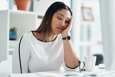 Buy stock photo Shot of a young businesswoman looking bored while sitting at a desk in an office