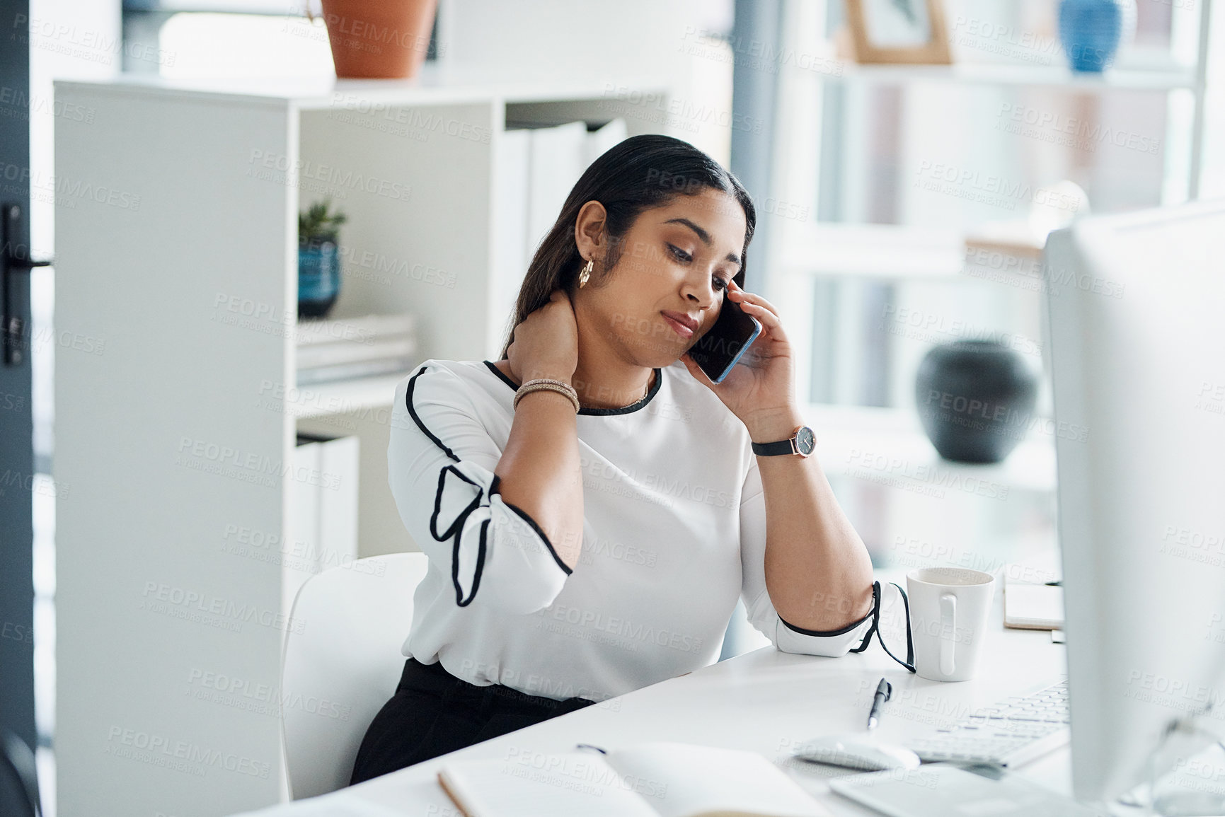 Buy stock photo Shot of a young businesswoman rubbing her neck while talking on a cellphone in an office
