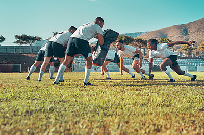 Buy stock photo Shot of a group of rugby players training with tackle bags on the field