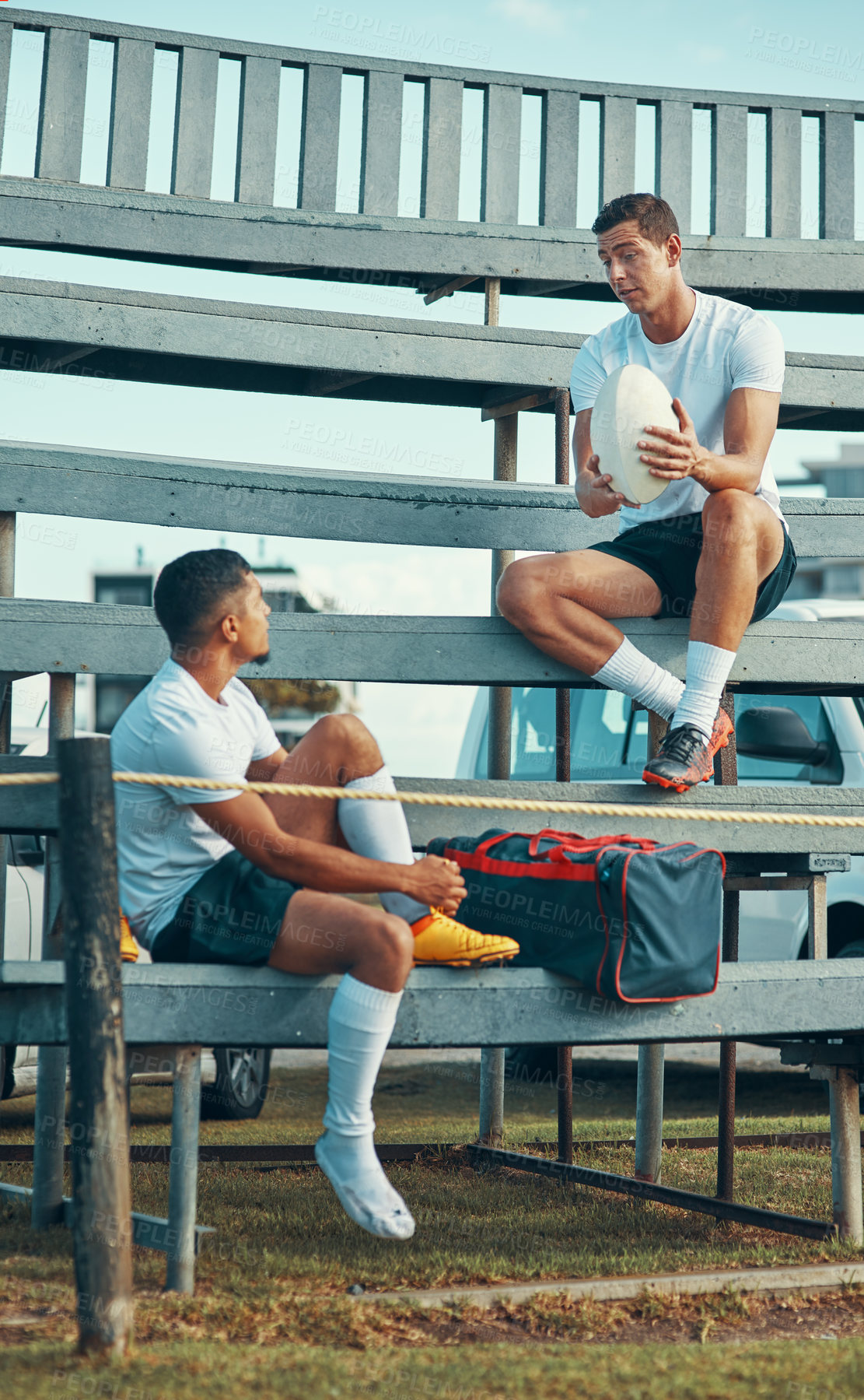 Buy stock photo Shot of two rugby players having a conversation while sitting on a bench