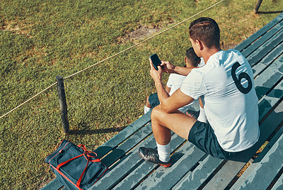 Buy stock photo Shot of a rugby player using his cellphone while sitting on the bench