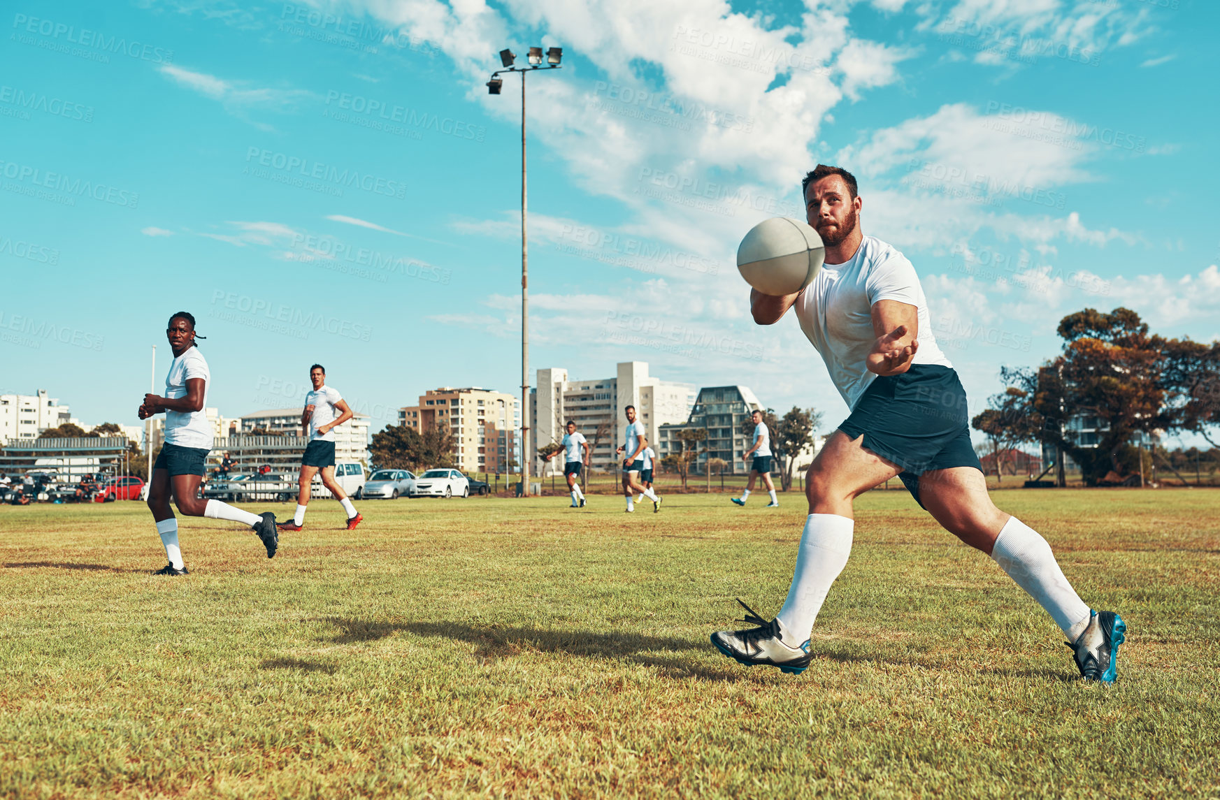 Buy stock photo Shot of young men playing a game of rugby on a field