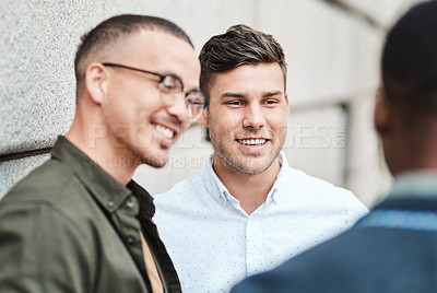 Buy stock photo Shot of three young businessmen having a discussion against an urban background