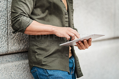 Buy stock photo Cropped shot of a businessman using a digital tablet against an urban background