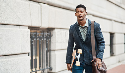Buy stock photo Shot of a young businessman holding a skateboard while walking through the city