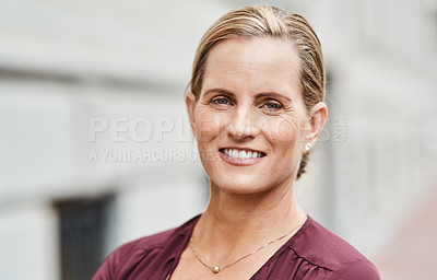 Buy stock photo Portrait of a mature businesswoman standing against an urban background
