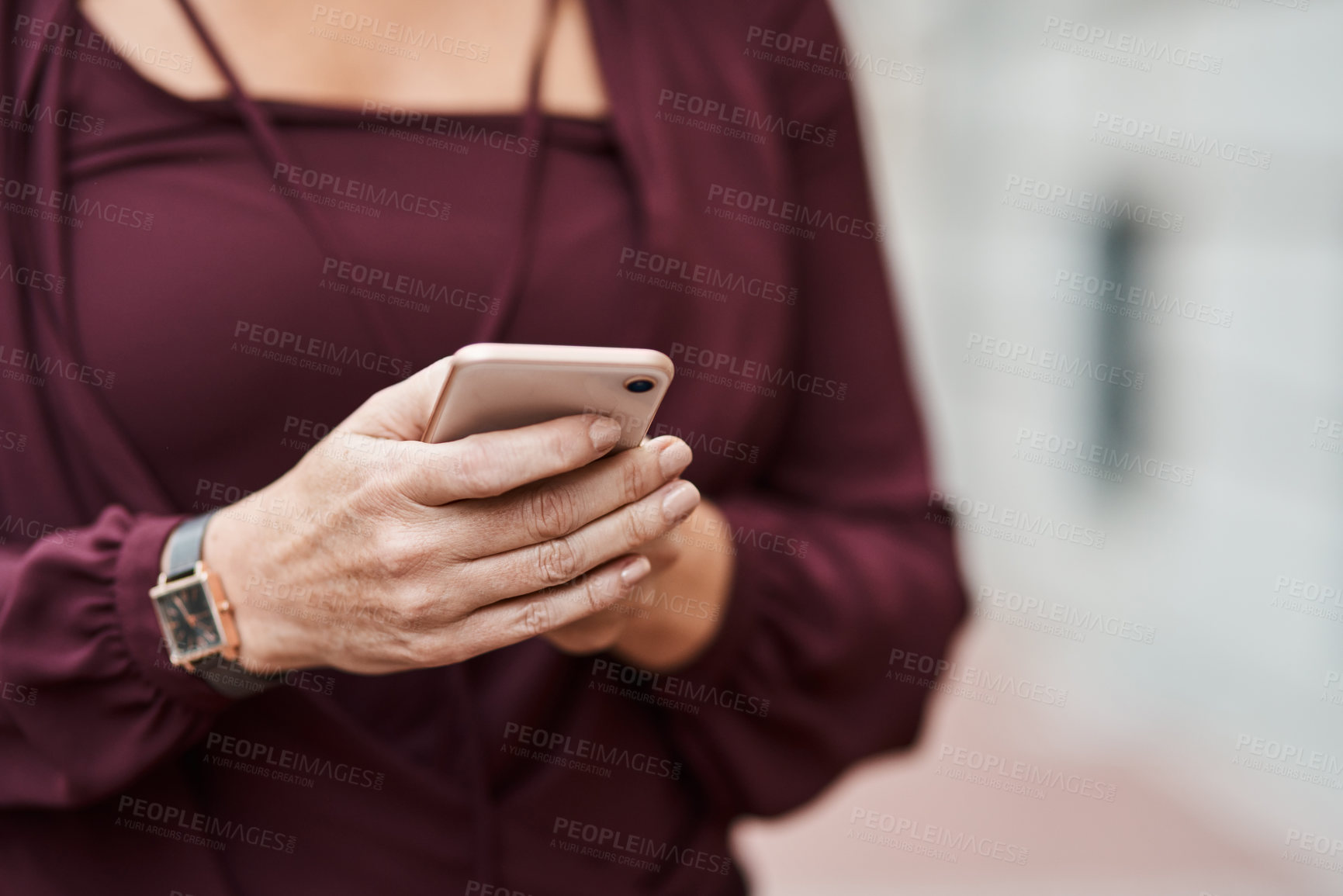 Buy stock photo Cropped shot of an unrecognisable businesswoman using a smartphone against an urban background