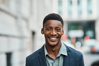 Buy stock photo Portrait of a confident young businessman standing against an urban background