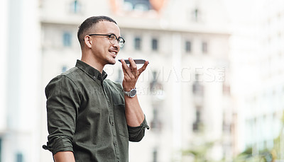 Buy stock photo Shot of a young businessman using a smartphone against an urban background