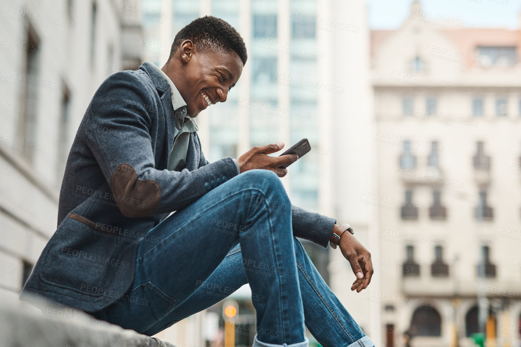 Buy stock photo Shot of a young businessman sitting on the curb and using a smartphone against an urban background