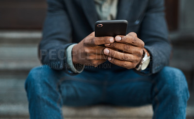 Buy stock photo Cropped shot of a businessman using a smartphone against an urban background