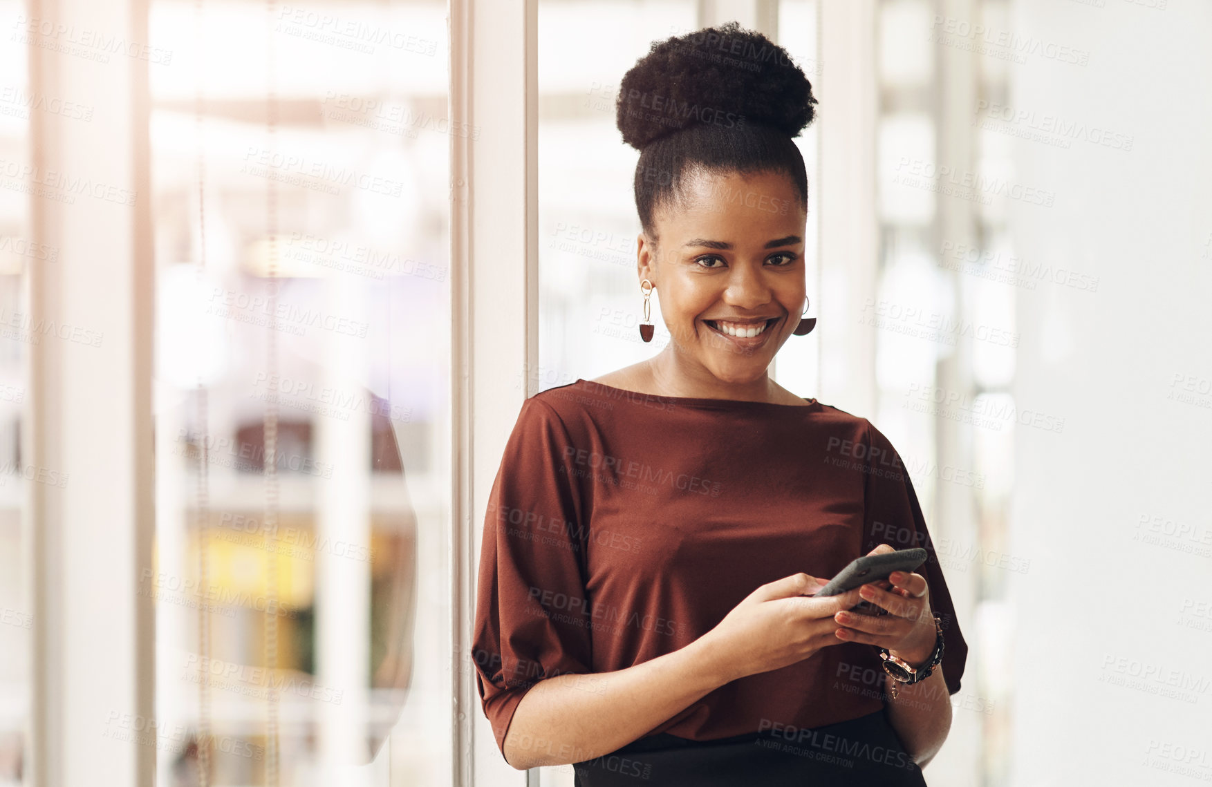 Buy stock photo Cropped portrait of an attractive young businesswoman using her cellphone while standing in the office