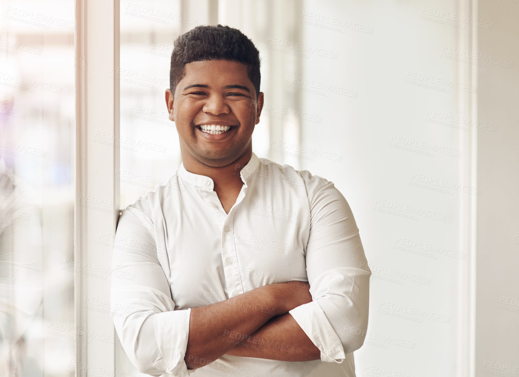 Buy stock photo Cropped portrait of a handsome young businessman standing with his arms crossed in the office