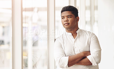 Buy stock photo Cropped shot of a handsome young businessman looking thoughtful while standing with his arms crossed in the office