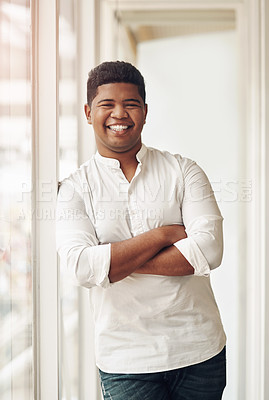 Buy stock photo Cropped portrait of a handsome young businessman standing with his arms crossed in the office