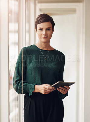 Buy stock photo Cropped portrait of an attractive young businesswoman using her tablet while standing in the office