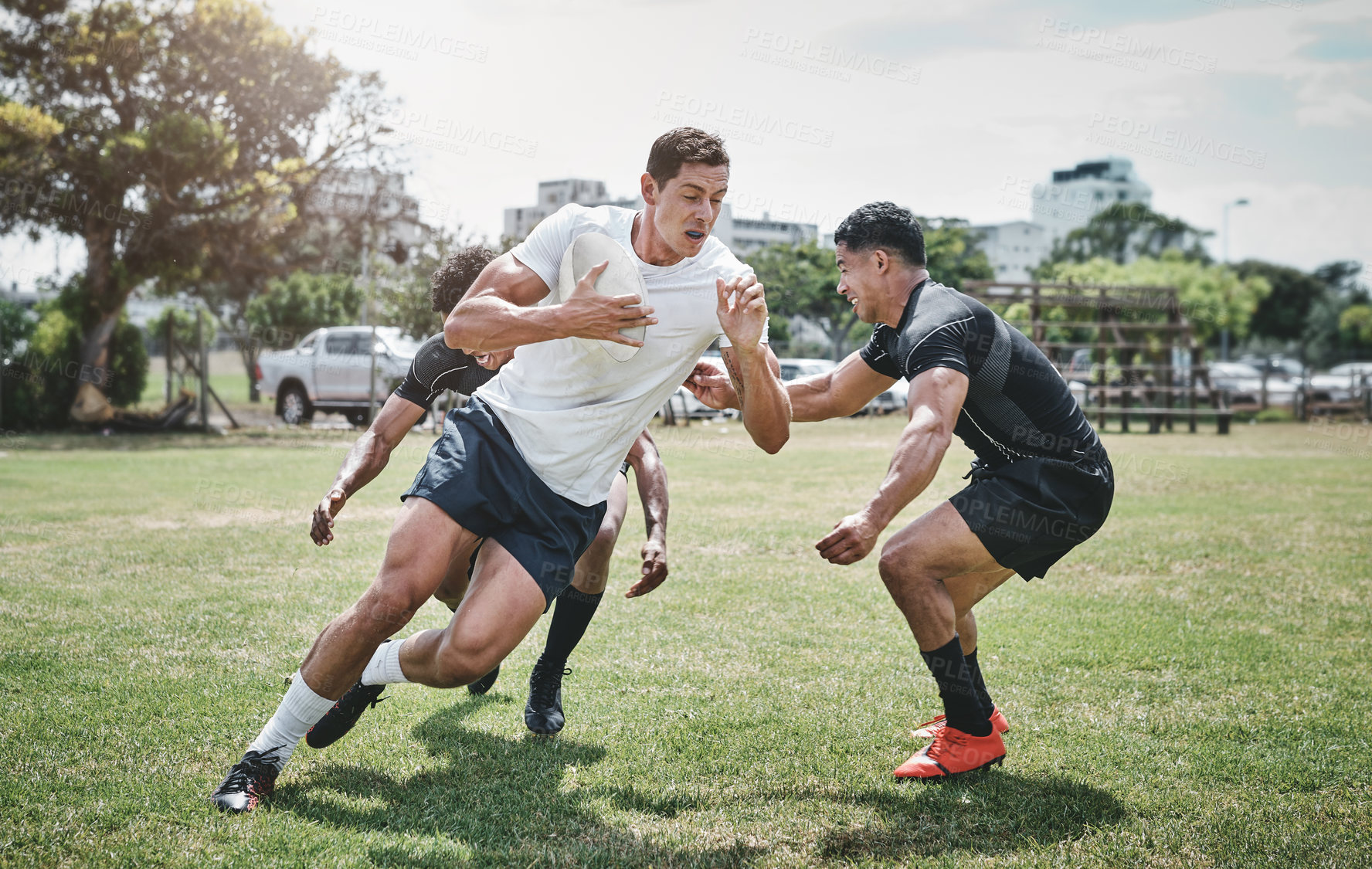 Buy stock photo Shot of a focused young rugby player competing against his opponents during a match outside on a filed