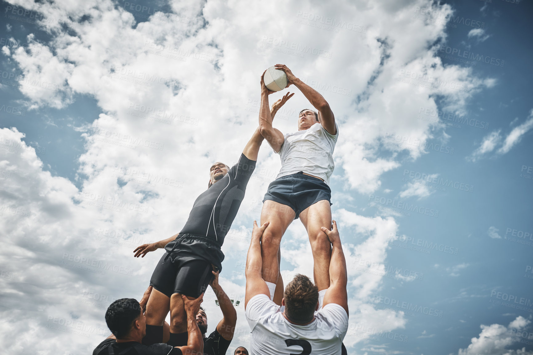 Buy stock photo Low angle shot of two rugby teams competing over a ball during a line out of a rugby match outside on a filed