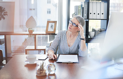 Buy stock photo Shot of a mature businesswoman going through paperwork in an office