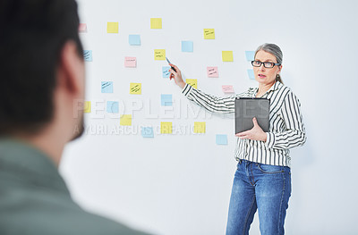 Buy stock photo Shot of a mature businesswoman giving a presentation with notes on a wall in an office
