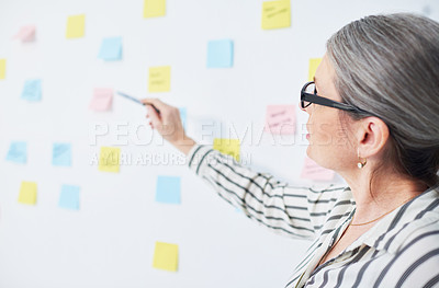 Buy stock photo Shot of a mature businesswoman brainstorming with notes on a wall in an office