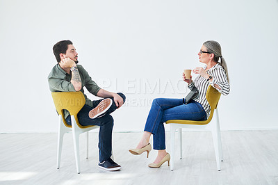Buy stock photo Shot of two businesspeople having a discussion while sitting on chairs in an office
