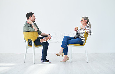 Buy stock photo Shot of two businesspeople having a discussion while sitting on chairs in an office