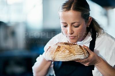 Buy stock photo Baker, pastry chef and cafe owner smelling a loaf of fresh baked bread in the kitchen of her coffee shop. Closeup of a female cook enjoying the aroma of a freshly made dough treat or consumables
