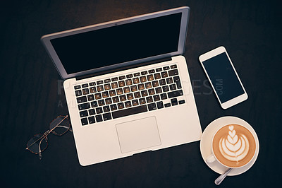 Buy stock photo Shot of a laptop, coffee and smartphone on a table in a cafe