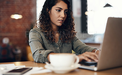 Buy stock photo Shot of a young woman using a laptop while working in a cafe