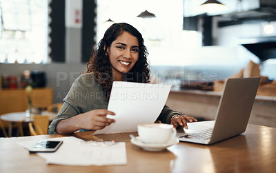 Buy stock photo Shot of a young woman using a laptop and going over paperwork in a cafe