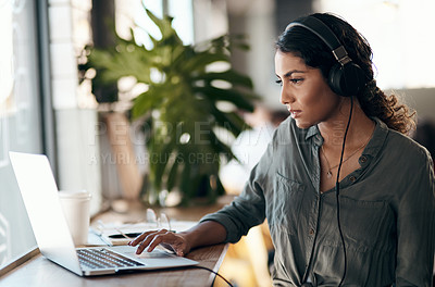 Buy stock photo Female student working on laptop with headphones for a university project in a cafe, restaurant or coffee shop. Thinking and studying young university or college woman typing and listening to music