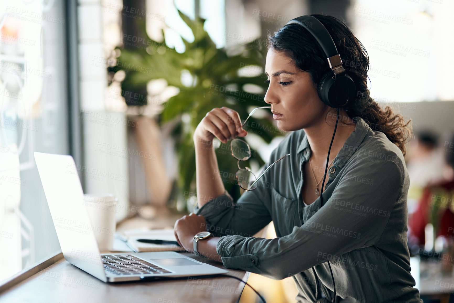 Buy stock photo Woman, headphones and reading with laptop at cafe for remote work, job search or online course. Young, female person or freelancer thinking with computer for research or virtual career at coffee shop