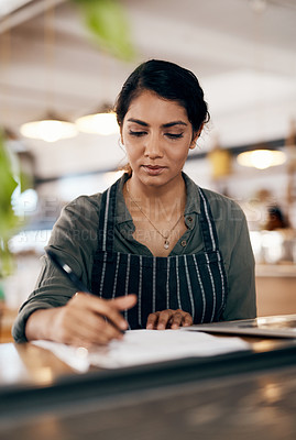 Buy stock photo Shot of a young woman going over paperwork while working in a cafe