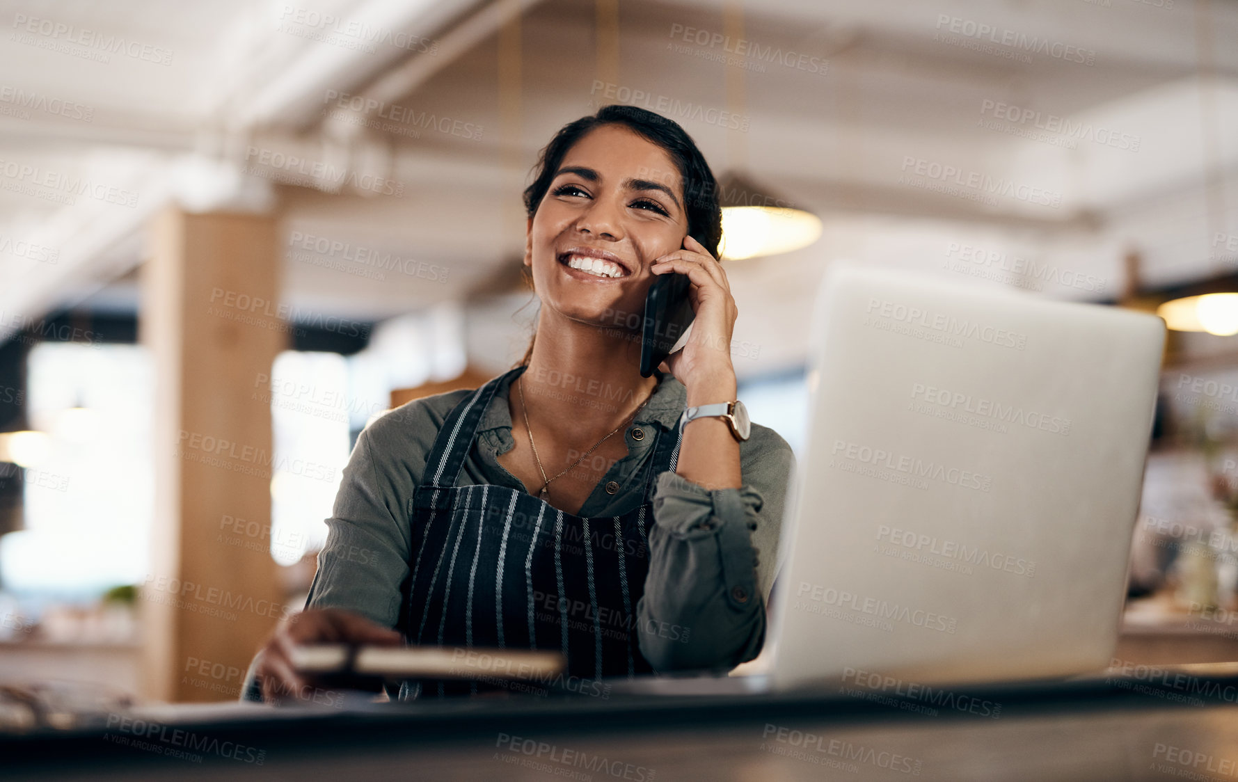 Buy stock photo Shot of a young woman using a laptop and smartphone while working in a cafe