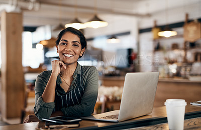 Buy stock photo Shot of a young woman using a laptop while working in a cafe